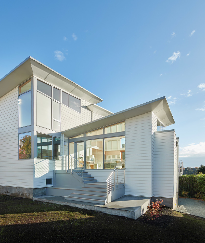 This is an example of a contemporary split-level white house exterior in Other with a shed roof.