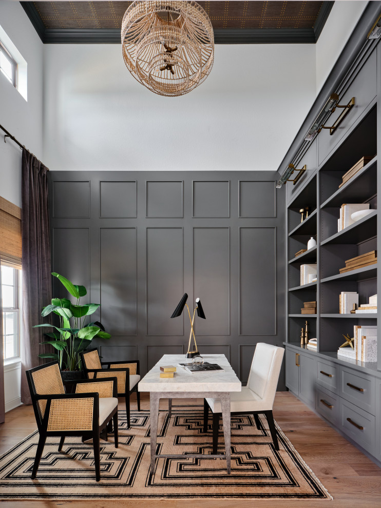 This is an example of a mid-sized transitional study room in Austin with grey walls, light hardwood floors, a freestanding desk, grey floor, wallpaper and decorative wall panelling.