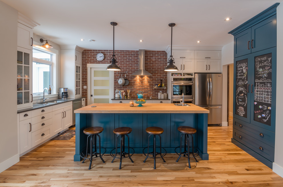 Inspiration for an industrial kitchen in Other with an undermount sink, shaker cabinets, blue cabinets, wood benchtops, red splashback, terra-cotta splashback, stainless steel appliances, light hardwood floors and with island.