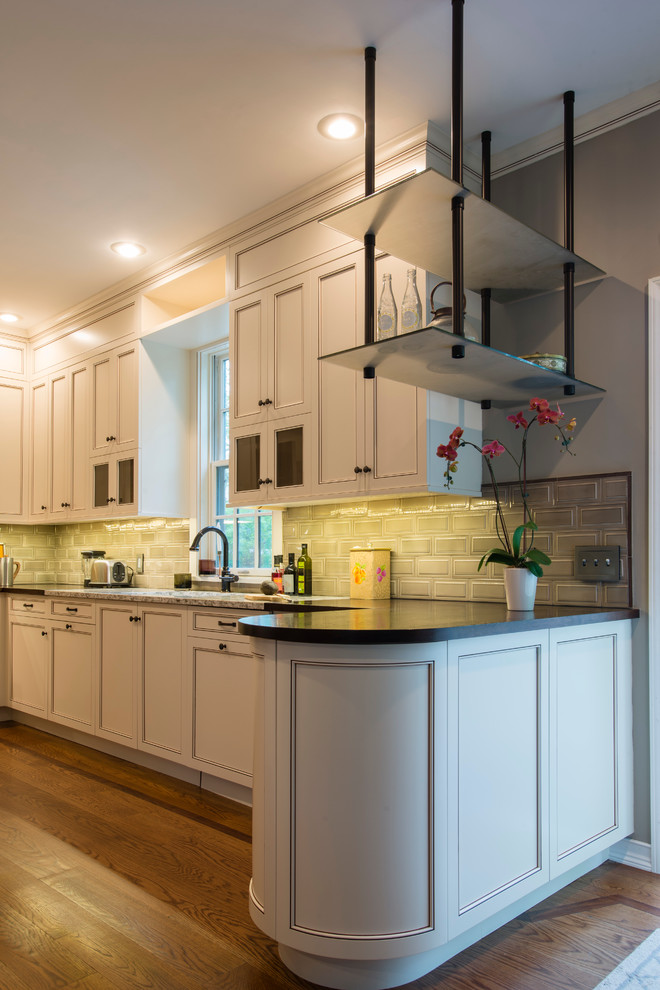 Inspiration for a mid-sized transitional u-shaped medium tone wood floor eat-in kitchen remodel in New York with an undermount sink, recessed-panel cabinets, white cabinets, subway tile backsplash, stainless steel appliances, a peninsula, granite countertops and beige backsplash