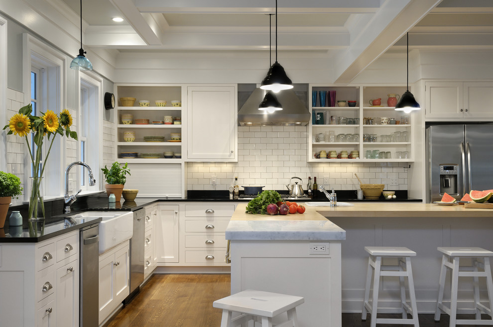 Country l-shaped kitchen in New York with a farmhouse sink, open cabinets, white cabinets, marble benchtops, white splashback, subway tile splashback and stainless steel appliances.