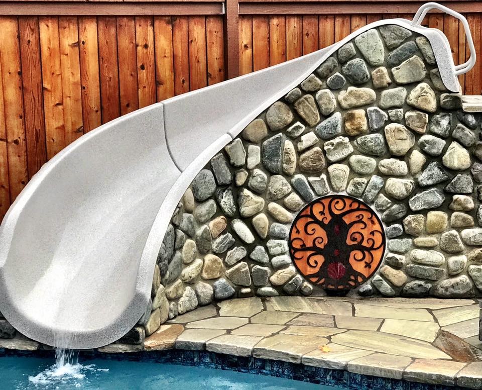 Example of an eclectic backyard stone and custom-shaped water slide design