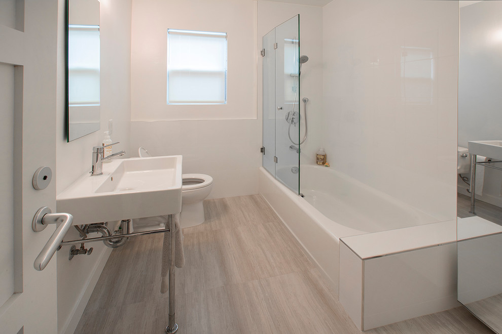 Photo of a small contemporary kids bathroom in Los Angeles with open cabinets, an alcove tub, a shower/bathtub combo, a two-piece toilet, white tile, porcelain tile, white walls, porcelain floors, a console sink, quartzite benchtops, brown floor, a hinged shower door and white benchtops.