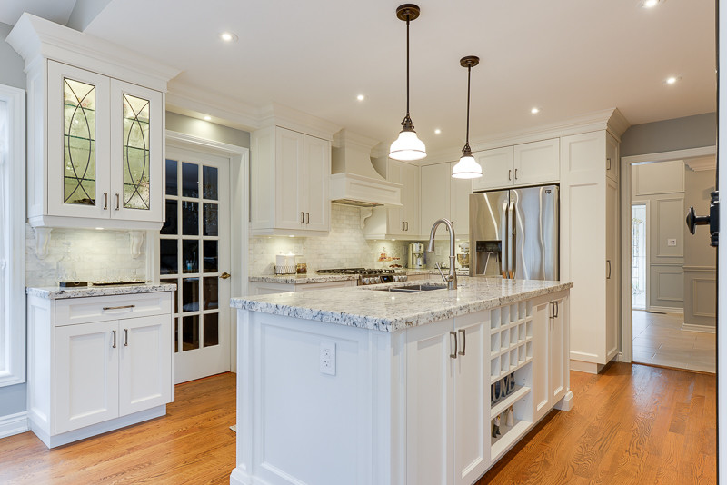 Transitional medium tone wood floor eat-in kitchen photo in Toronto with recessed-panel cabinets, white cabinets, granite countertops, white backsplash, marble backsplash and an island