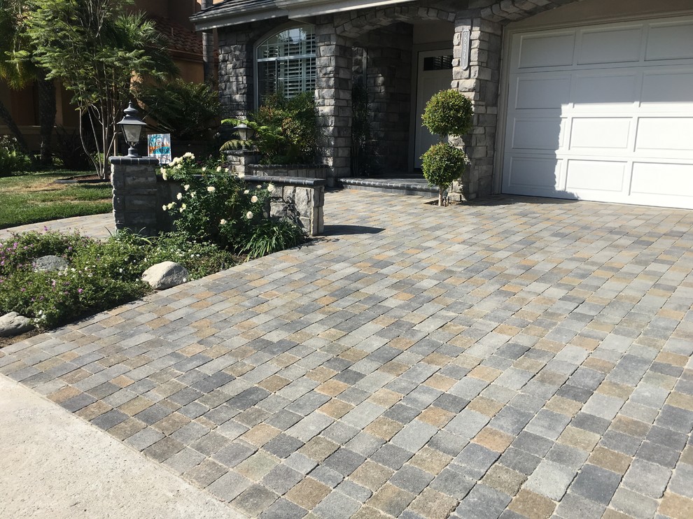 This is an example of a mid-sized traditional front yard driveway in Orange County with concrete pavers.