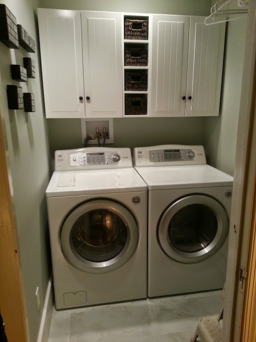 Inspiration for a small eclectic single-wall dedicated laundry room in New York with raised-panel cabinets, white cabinets, green walls, ceramic floors and a side-by-side washer and dryer.