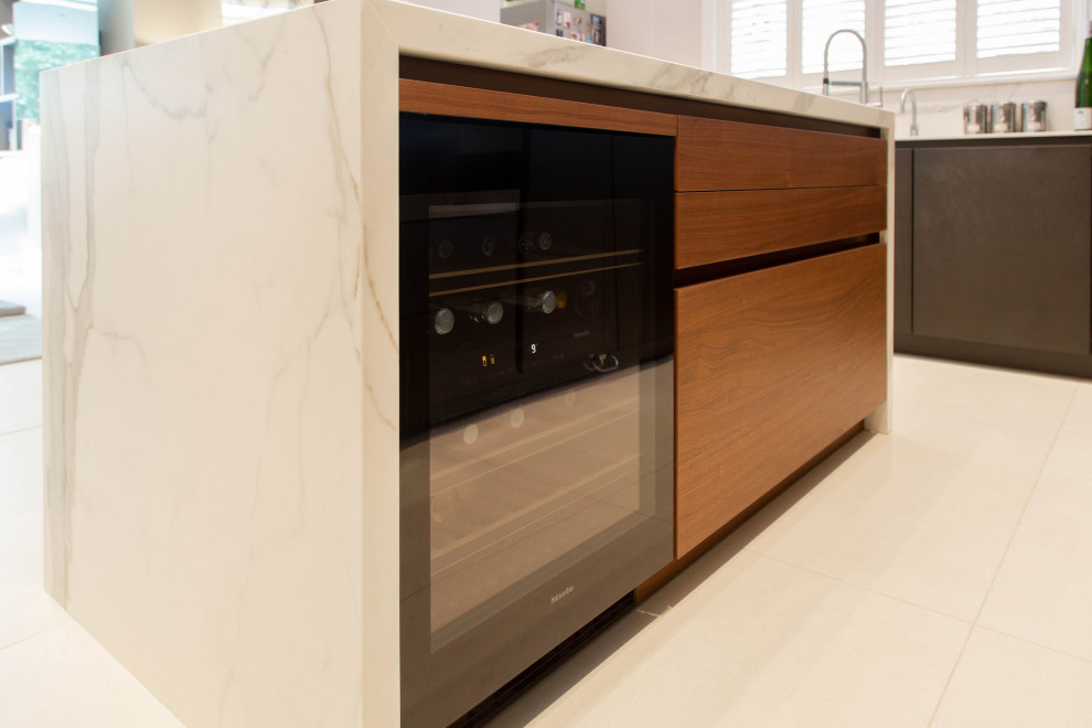Photo of a small contemporary l-shaped separate kitchen in London with a drop-in sink, flat-panel cabinets, black cabinets, panelled appliances, ceramic floors, a peninsula, beige floor, white benchtop and coffered.