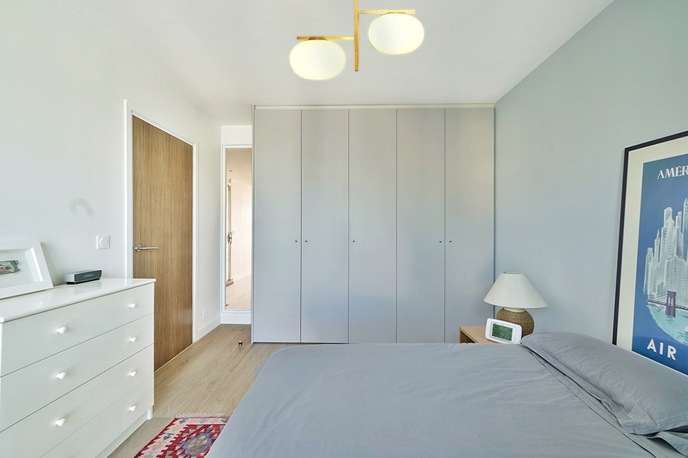 Design ideas for a mid-sized contemporary master bedroom in Paris with blue walls, light hardwood floors and brown floor.