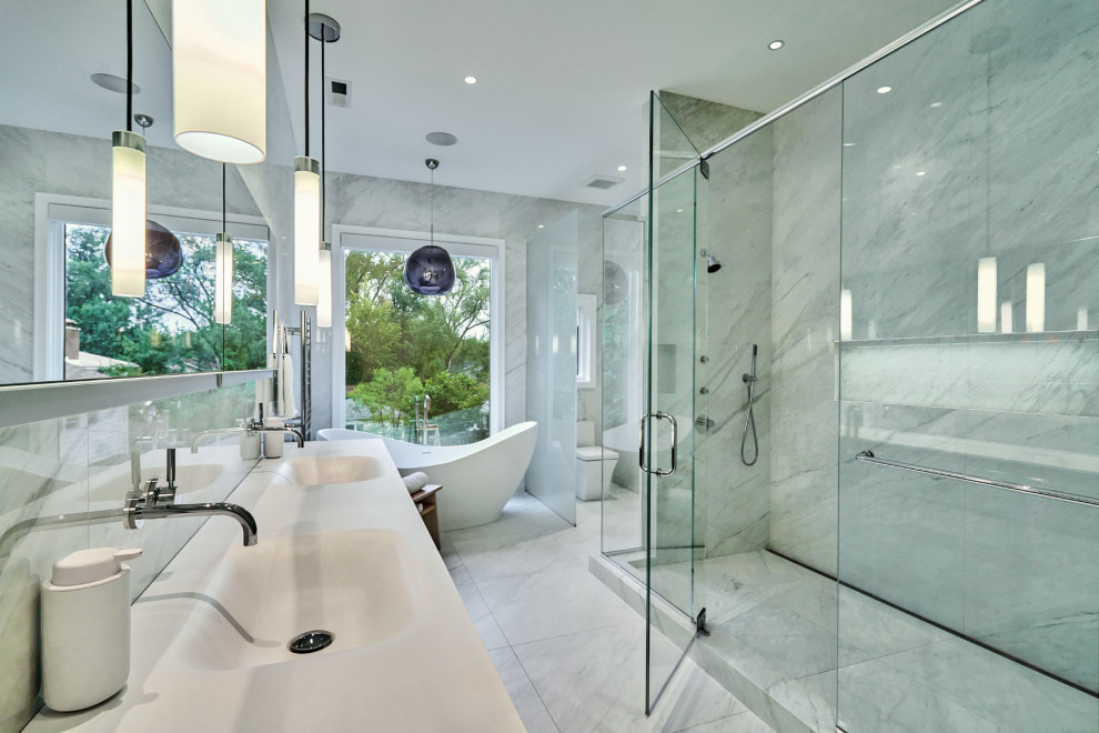 This is an example of a large modern master bathroom in Chicago with flat-panel cabinets, grey cabinets, a freestanding tub, a double shower, a one-piece toilet, white tile, porcelain tile, white walls, porcelain floors, an integrated sink, solid surface benchtops, white floor, a hinged shower door, white benchtops, a niche, a double vanity and a floating vanity.