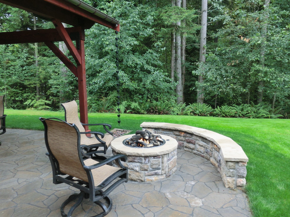 Photo of a large eclectic backyard patio in Seattle with a fire feature and concrete pavers.
