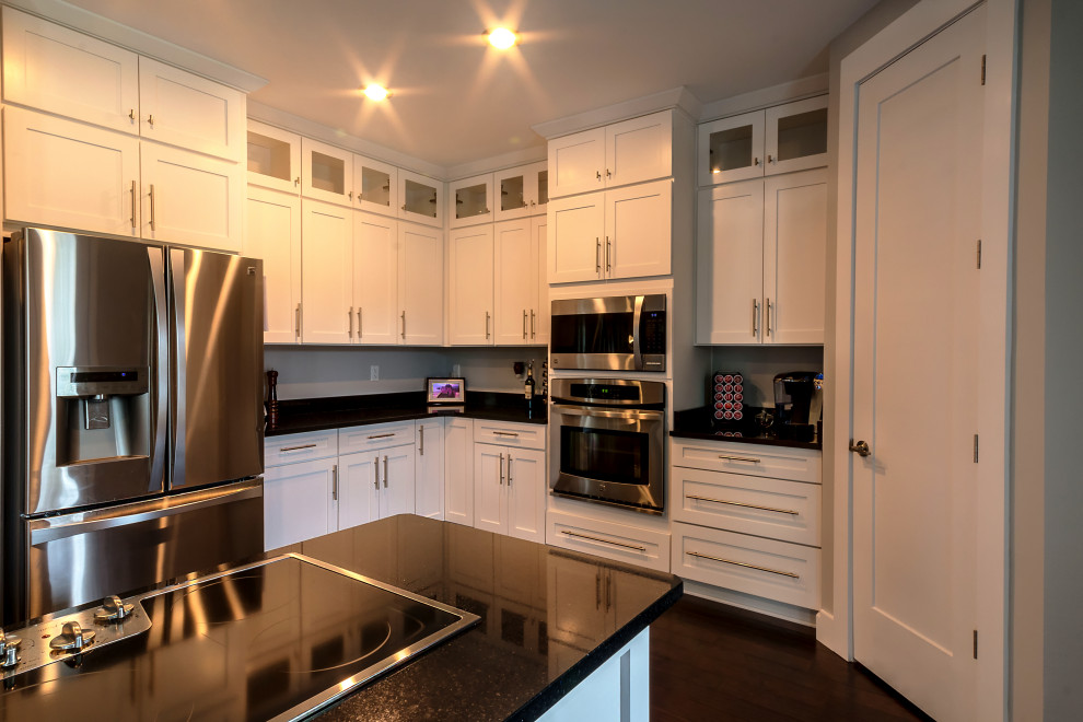 Inspiration for a large l-shaped eat-in kitchen remodel with an undermount sink, shaker cabinets, white cabinets, granite countertops, an island and black countertops