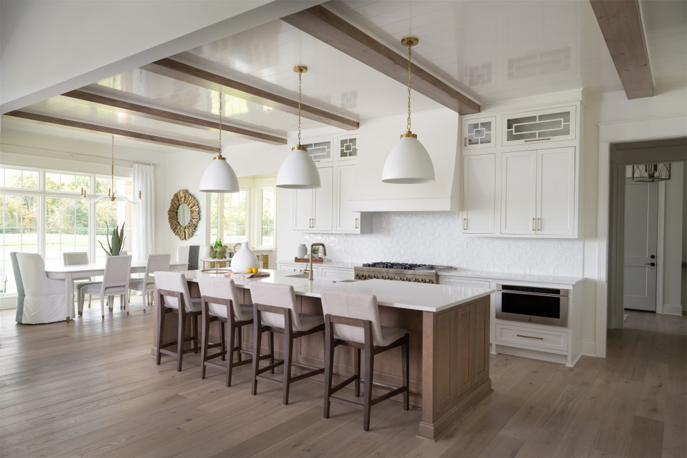 Photo of a medium sized traditional l-shaped open plan kitchen in Indianapolis with a submerged sink, shaker cabinets, white cabinets, engineered stone countertops, white splashback, stainless steel appliances, an island, white worktops, brown floors, exposed beams and a timber clad ceiling.