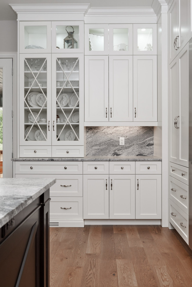 Huge transitional light wood floor and brown floor eat-in kitchen photo in Toronto with a farmhouse sink, shaker cabinets, white cabinets, granite countertops, gray backsplash, granite backsplash, stainless steel appliances, an island and gray countertops