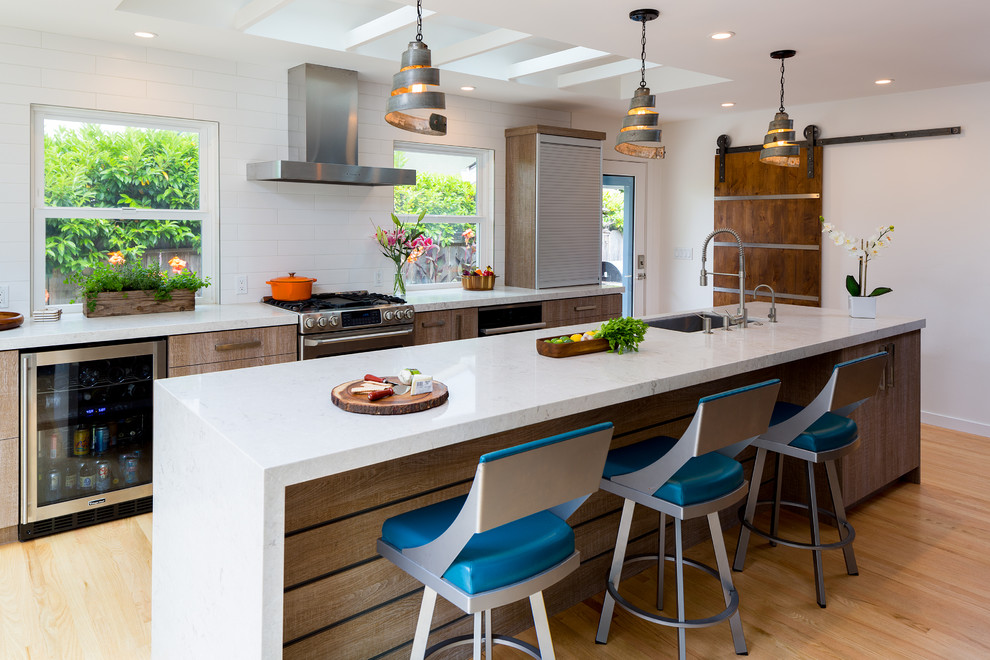 Mid-sized contemporary galley eat-in kitchen in Other with a single-bowl sink, flat-panel cabinets, medium wood cabinets, quartz benchtops, white splashback, subway tile splashback, stainless steel appliances, light hardwood floors, with island and brown floor.