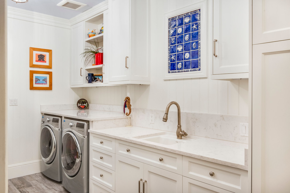 This is an example of a beach style laundry room in Los Angeles with recessed-panel cabinets, white cabinets and a side-by-side washer and dryer.