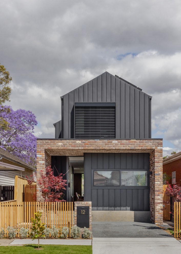 Photo of a mid-sized contemporary two-storey black house exterior in Sydney with metal siding and a gable roof.