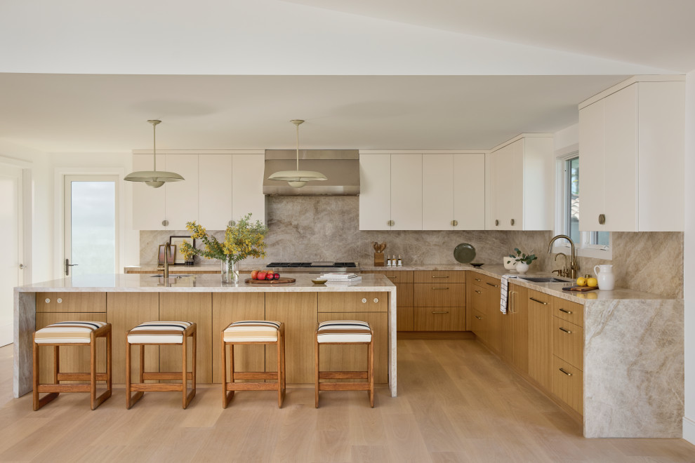 Eat-in kitchen - large contemporary u-shaped light wood floor, brown floor and vaulted ceiling eat-in kitchen idea in Los Angeles with a single-bowl sink, flat-panel cabinets, light wood cabinets, quartzite countertops, beige backsplash, stone slab backsplash, paneled appliances, an island and beige countertops