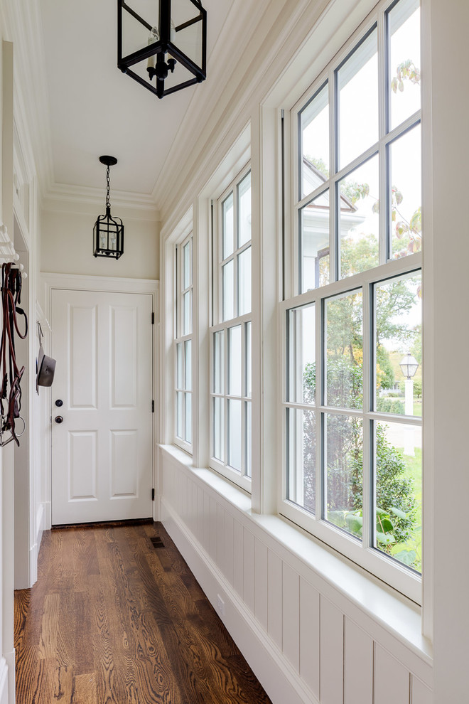 This is an example of a mid-sized country hallway in Boston with white walls, medium hardwood floors and brown floor.