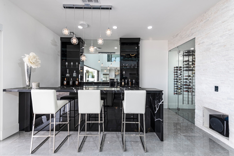 This is an example of an expansive contemporary galley breakfast bar in Las Vegas with a built-in sink, flat-panel cabinets, black cabinets, granite worktops, mirror splashback and black worktops.