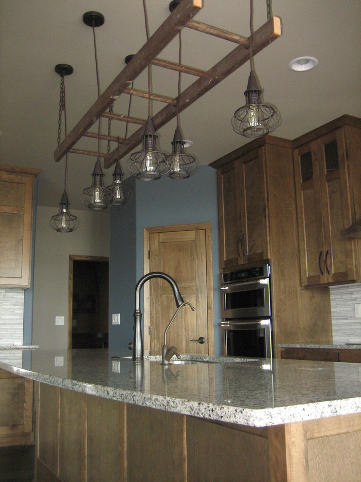 Open concept kitchen - mid-sized rustic l-shaped dark wood floor open concept kitchen idea with an undermount sink, recessed-panel cabinets, medium tone wood cabinets, granite countertops, gray backsplash, glass tile backsplash, stainless steel appliances and an island