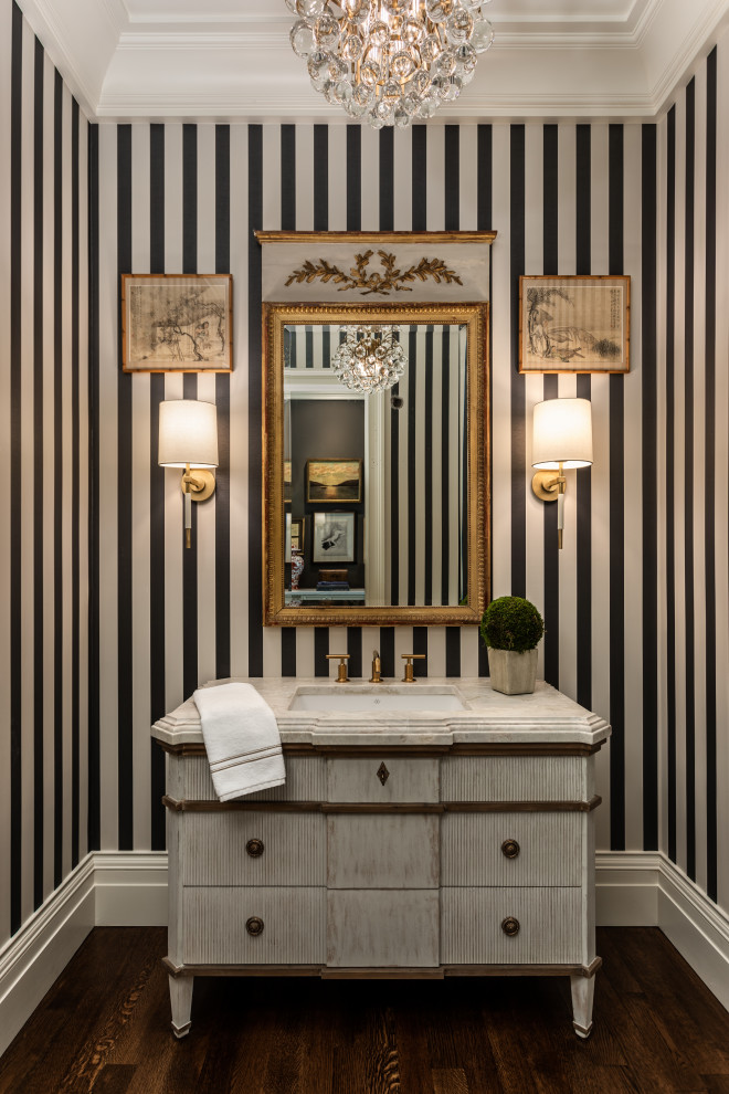 Powder room - mid-sized transitional dark wood floor and brown floor powder room idea with furniture-like cabinets, gray cabinets, a two-piece toilet, multicolored walls, an undermount sink, marble countertops and white countertops