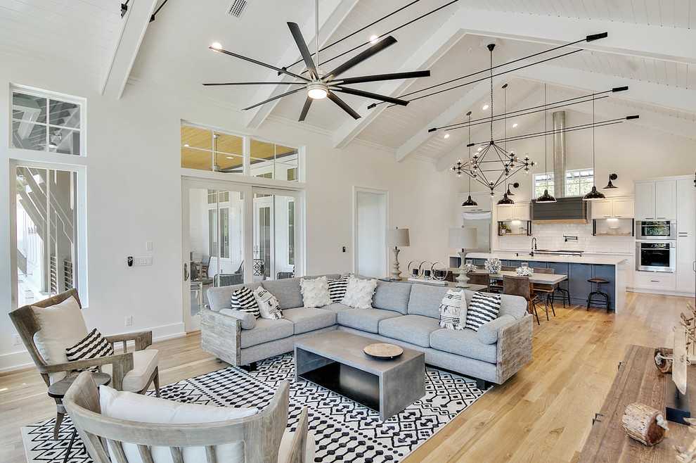 This is an example of a beach style open concept living room in Miami with white walls, medium hardwood floors, no fireplace, no tv and brown floor.