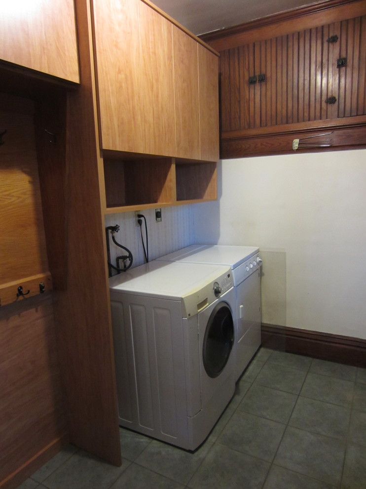 Photo of a mid-sized traditional single-wall dedicated laundry room in Other with flat-panel cabinets, medium wood cabinets, white walls, ceramic floors and a side-by-side washer and dryer.