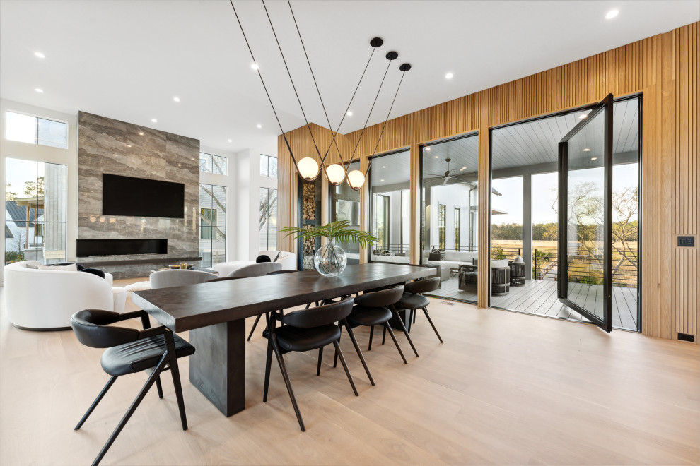 Photo of an expansive modern open plan dining room in Charleston with white walls, light hardwood flooring, panelled walls, a tiled fireplace surround and a corner fireplace.