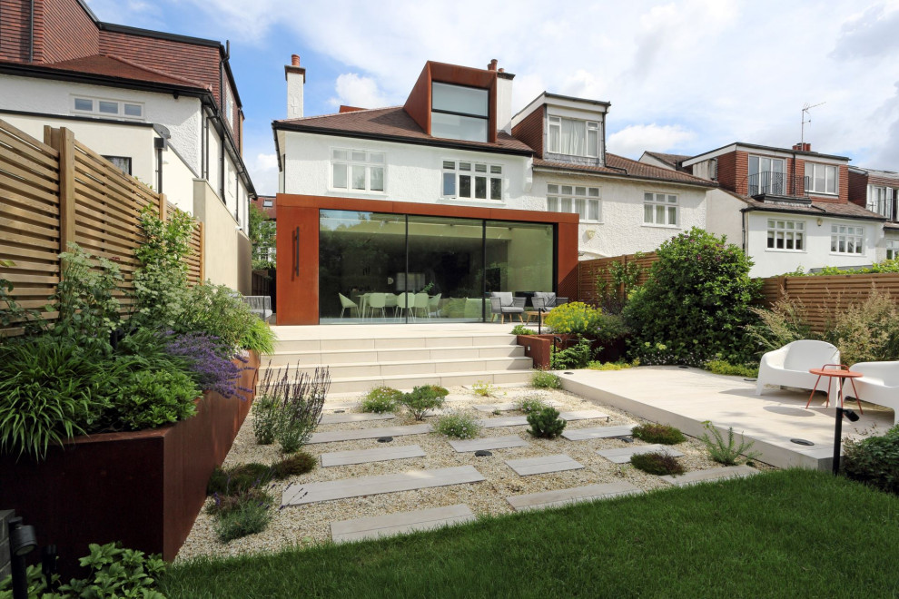 Photo of a large modern back formal partial sun garden for summer in London with a living wall, decking and a wood fence.