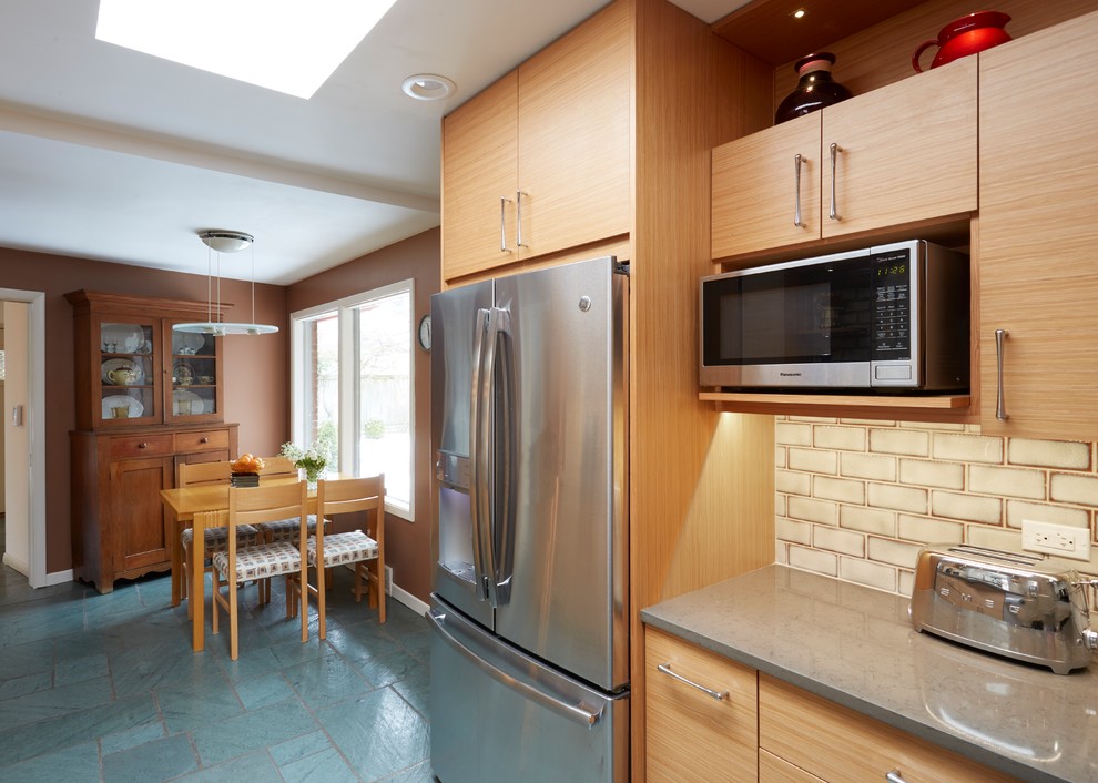 This is an example of a mid-sized midcentury galley separate kitchen in Chicago with a double-bowl sink, flat-panel cabinets, medium wood cabinets, quartz benchtops, beige splashback, subway tile splashback, stainless steel appliances, slate floors, no island and blue floor.