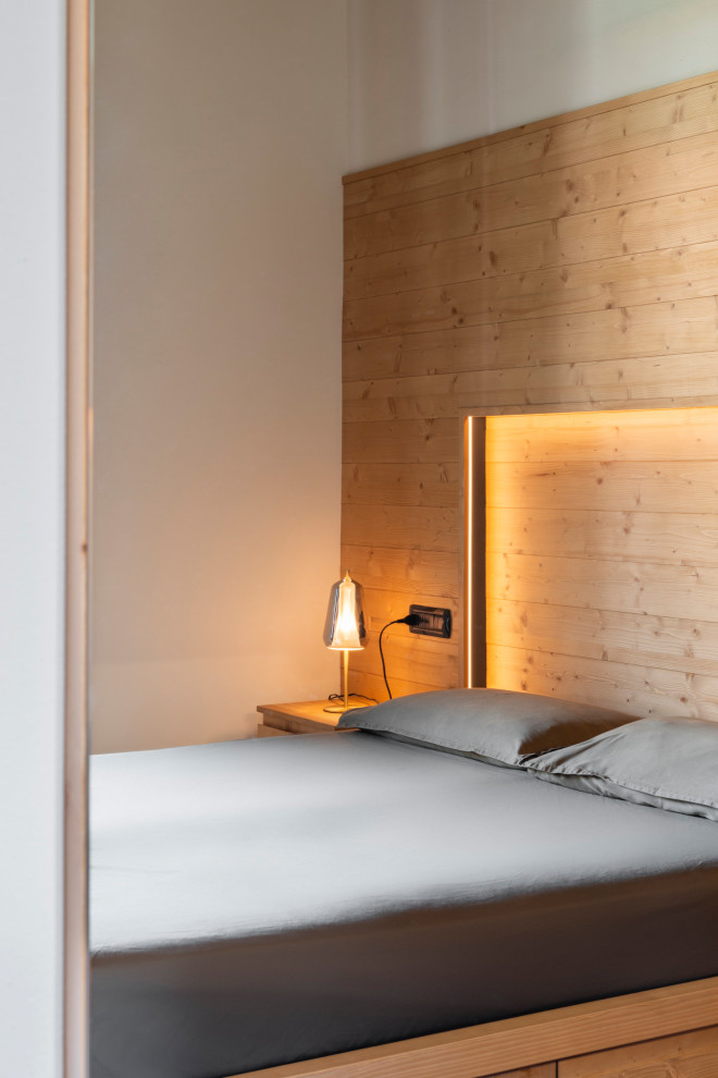Imagen de dormitorio principal rústico pequeño con paredes grises, suelo laminado, suelo marrón, madera y madera