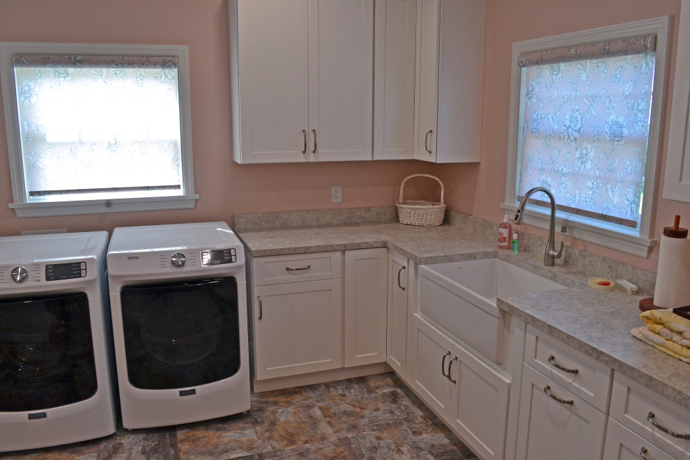 This is an example of a large traditional l-shaped separated utility room in Other with a belfast sink, shaker cabinets, white cabinets, laminate countertops, pink walls, ceramic flooring, a side by side washer and dryer, multi-coloured floors and pink worktops.