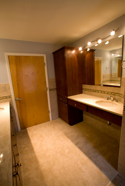 This is an example of a mid-sized transitional master bathroom in Indianapolis with an undermount sink, flat-panel cabinets, dark wood cabinets, marble benchtops, an alcove shower, a one-piece toilet, beige tile, ceramic tile, beige walls and ceramic floors.