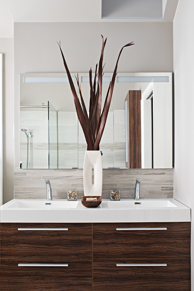 Photo of a mid-sized tropical master bathroom in Toronto with an integrated sink, flat-panel cabinets, medium wood cabinets, solid surface benchtops, a freestanding tub, a corner shower, a one-piece toilet, beige tile, ceramic tile, grey walls and ceramic floors.