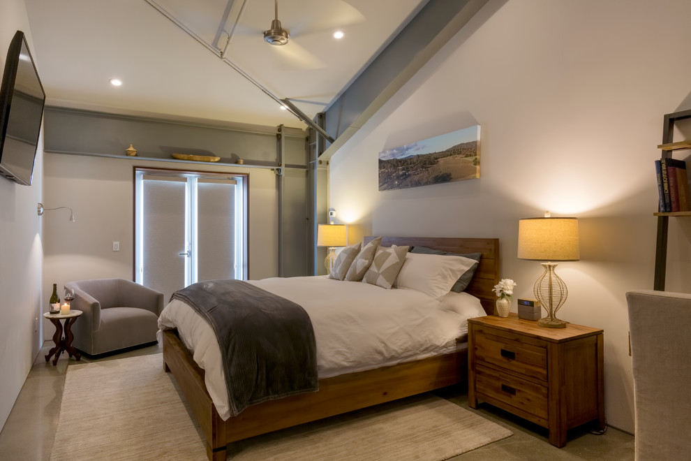 Inspiration for a large industrial loft-style bedroom in San Francisco with white walls, concrete floors and grey floor.