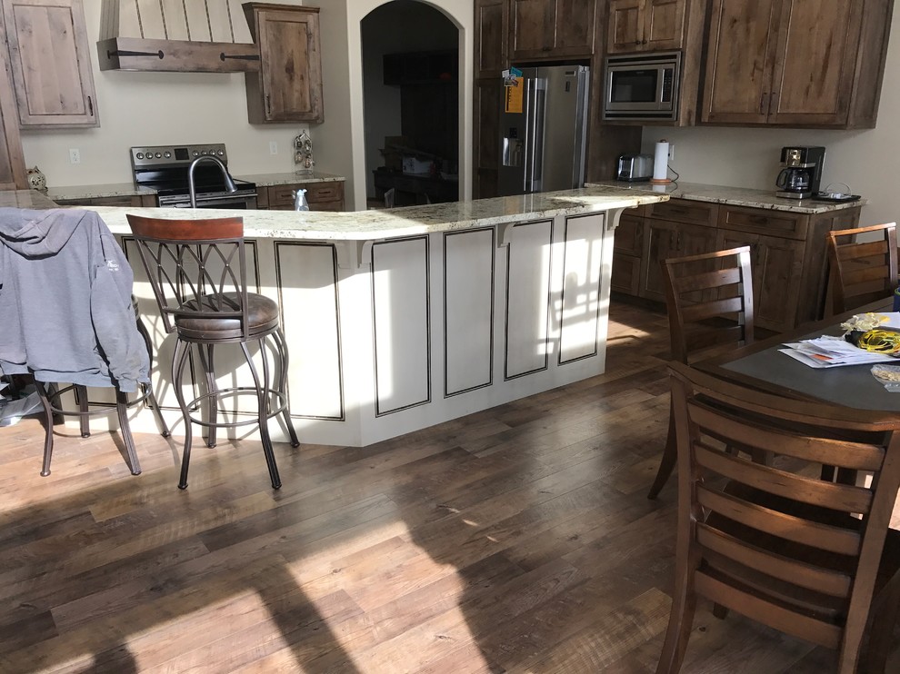 Large elegant u-shaped dark wood floor and brown floor open concept kitchen photo with flat-panel cabinets, distressed cabinets, granite countertops, a double-bowl sink, stainless steel appliances and an island