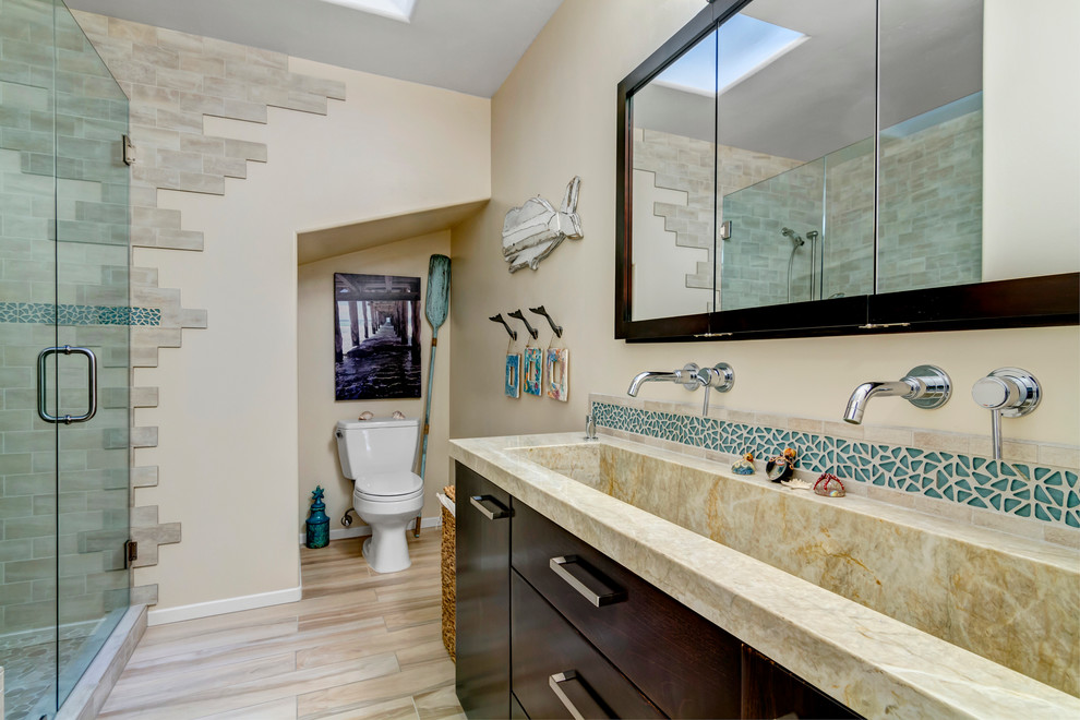 This is an example of a small beach style kids bathroom in San Diego with a trough sink, flat-panel cabinets, dark wood cabinets, quartzite benchtops, an alcove shower, a two-piece toilet, multi-coloured tile, porcelain tile, beige walls and porcelain floors.