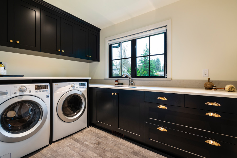 Design ideas for a mid-sized country l-shaped dedicated laundry room in Vancouver with an undermount sink, shaker cabinets, black cabinets, quartz benchtops, beige walls, porcelain floors, a side-by-side washer and dryer, beige floor and white benchtop.