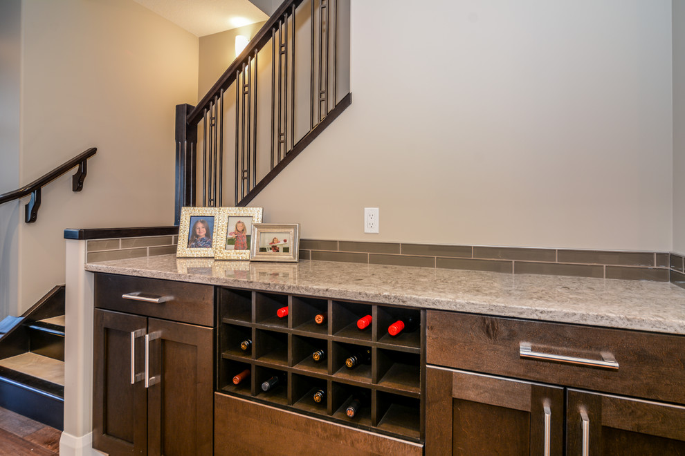 Example of a mid-sized transitional single-wall medium tone wood floor open concept kitchen design in Calgary with an undermount sink, shaker cabinets, white cabinets, granite countertops, gray backsplash, porcelain backsplash, stainless steel appliances and an island