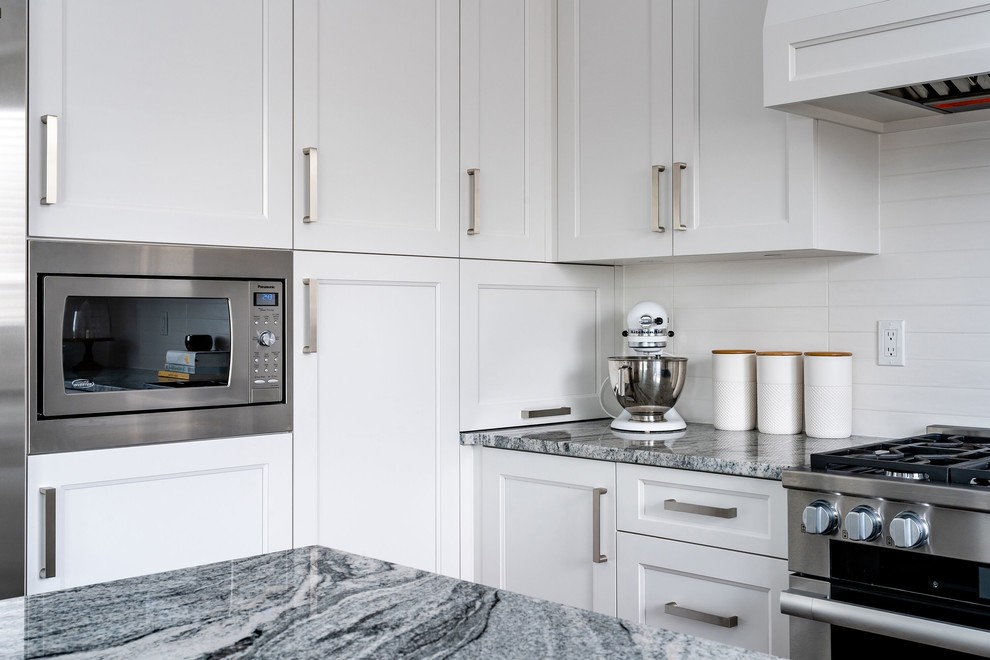 Inspiration for a large transitional u-shaped medium tone wood floor and brown floor eat-in kitchen remodel in Vancouver with an undermount sink, recessed-panel cabinets, white cabinets, granite countertops, white backsplash, subway tile backsplash, stainless steel appliances, an island and multicolored countertops