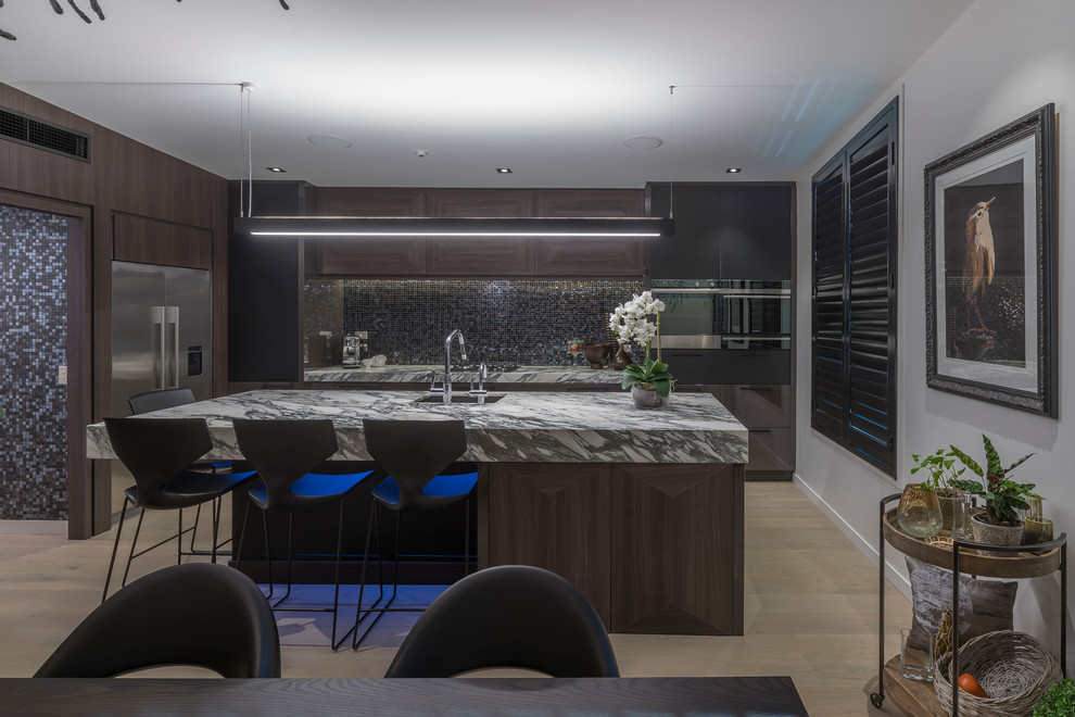 Photo of a large contemporary l-shaped eat-in kitchen in Hamilton with an undermount sink, flat-panel cabinets, brown cabinets, stainless steel benchtops, multi-coloured splashback, mosaic tile splashback, stainless steel appliances, with island, beige floor and light hardwood floors.