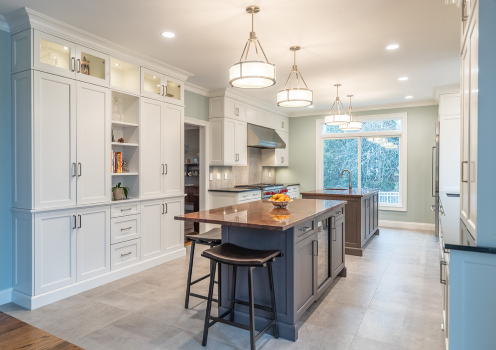 Inspiration for a large transitional galley open plan kitchen in Bridgeport with an undermount sink, recessed-panel cabinets, white cabinets, granite benchtops, grey splashback, ceramic splashback, stainless steel appliances, ceramic floors, multiple islands, grey floor and black benchtop.