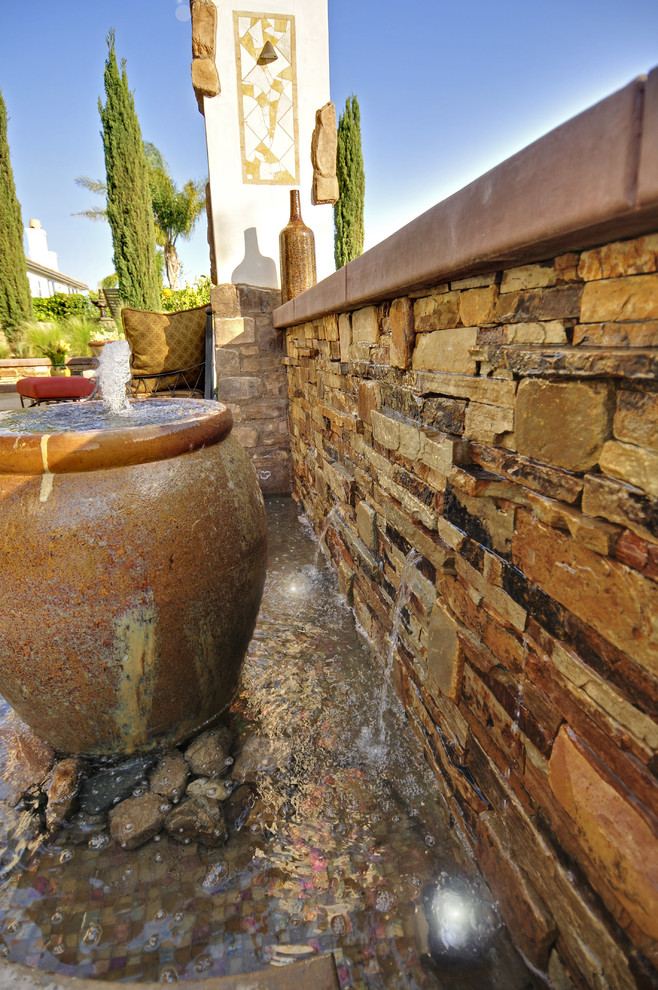 Esempio di un grande patio o portico mediterraneo dietro casa con fontane, lastre di cemento e una pergola