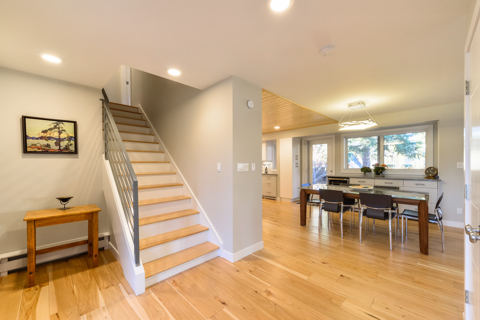 Foyer - mid-sized modern light wood floor and beige floor foyer idea in Calgary with beige walls and a white front door
