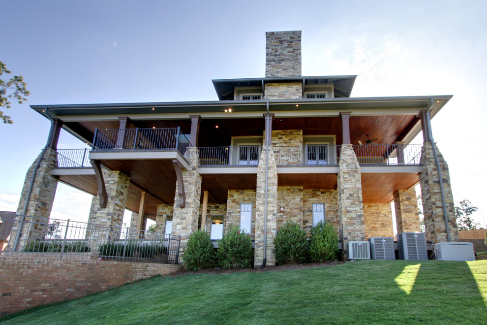 Photo of an expansive arts and crafts two-storey exterior in Other with stone veneer.