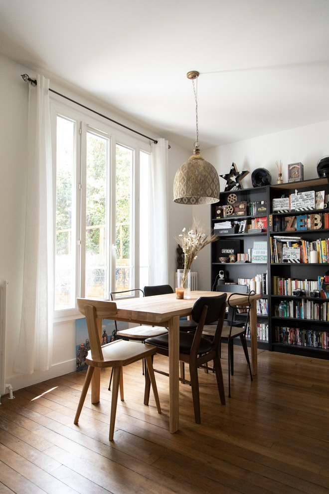 Aménagement d'une grande salle à manger ouverte sur le salon industrielle avec un mur blanc, parquet foncé et un sol marron.