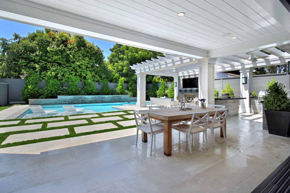 Large rural back patio in Los Angeles with an outdoor kitchen, natural stone paving and a pergola.
