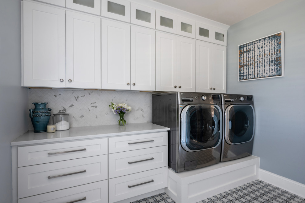 シャーロットにあるお手頃価格の小さなトランジショナルスタイルのおしゃれな洗濯室 (ll型、シェーカースタイル扉のキャビネット、白いキャビネット、クオーツストーンカウンター、白いキッチンパネル、大理石のキッチンパネル、青い壁、磁器タイルの床、左右配置の洗濯機・乾燥機、青い床、白いキッチンカウンター) の写真