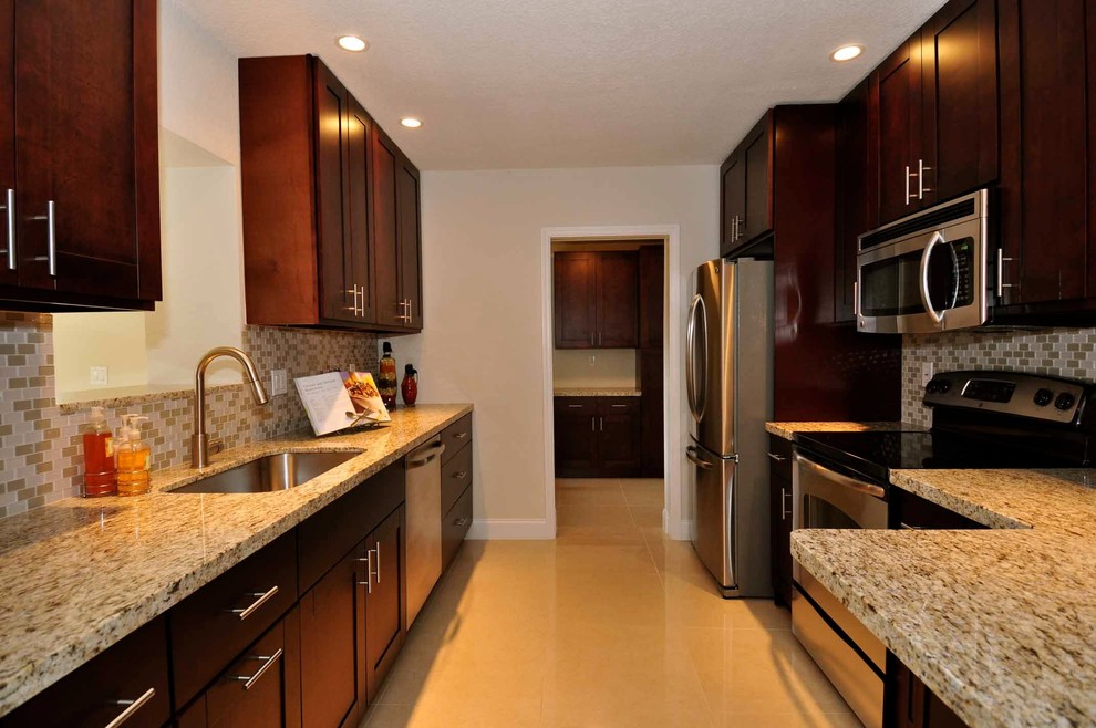 Eat-in kitchen - mid-sized transitional galley porcelain tile eat-in kitchen idea in Miami with an undermount sink, shaker cabinets, dark wood cabinets, wood countertops, brown backsplash, glass tile backsplash, stainless steel appliances and a peninsula