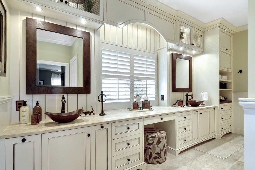 Design ideas for a large transitional master bathroom in Charleston with a vessel sink, recessed-panel cabinets, beige cabinets, a freestanding tub, a corner shower, gray tile, stone tile, beige walls, porcelain floors, beige floor and a hinged shower door.